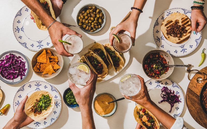 Taco Tuesday Triumphs, peoples hands cheersing over tacos