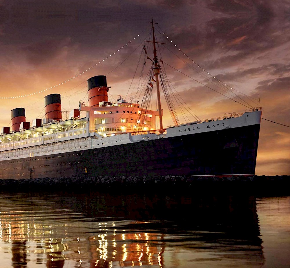 The historic Queen Mary ship docked in Long Beach with a sunset backdrop.