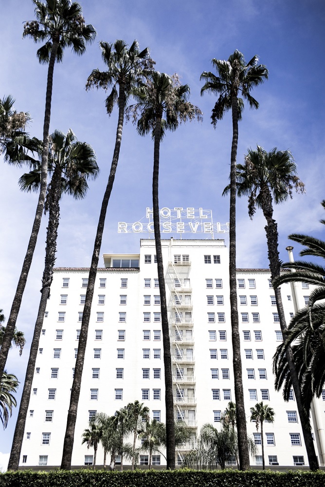 The classic neon sign of The Hollywood Roosevelt Hotel with LA's night sky in the background.