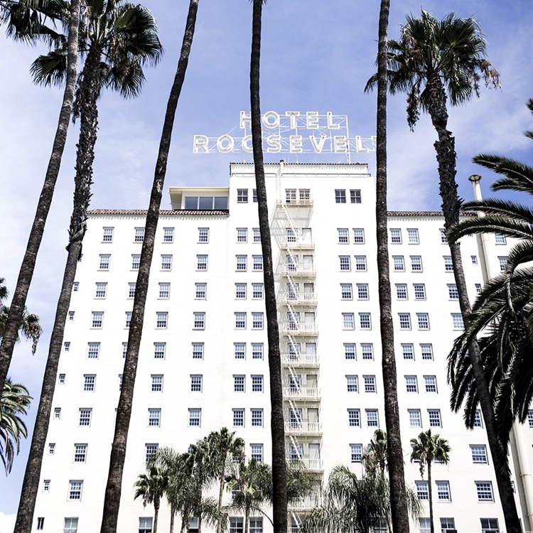 The classic neon sign of The Hollywood Roosevelt Hotel with LA's night sky in the background.