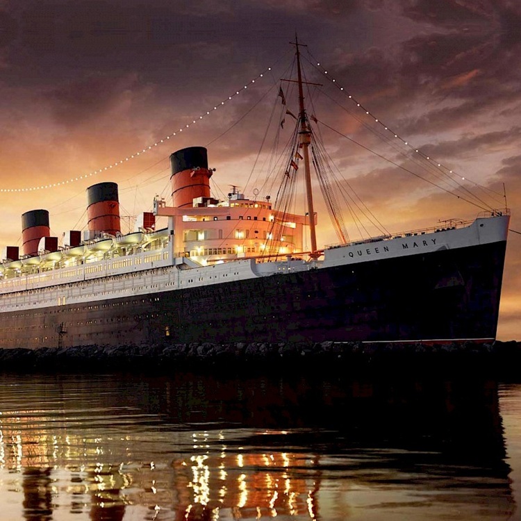 The historic Queen Mary ship docked in Long Beach with a sunset backdrop.