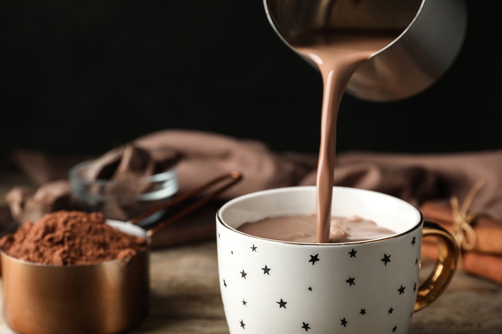 Pouring,Hot,Cocoa,Drink,Into,Cup,On,Wooden,Table