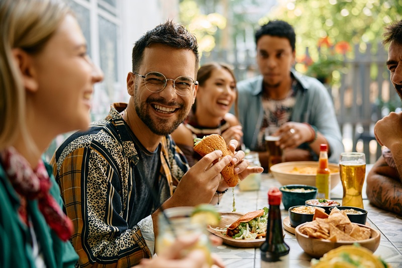 Happy,Man,Eating,Tacos,And,Talking,To,His,Friends,During